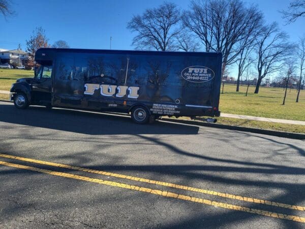 A Fuji moving truck is parked on the side of a road in a park area with bare trees and a clear blue sky.