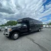 Black shuttle bus parked among other vehicles.