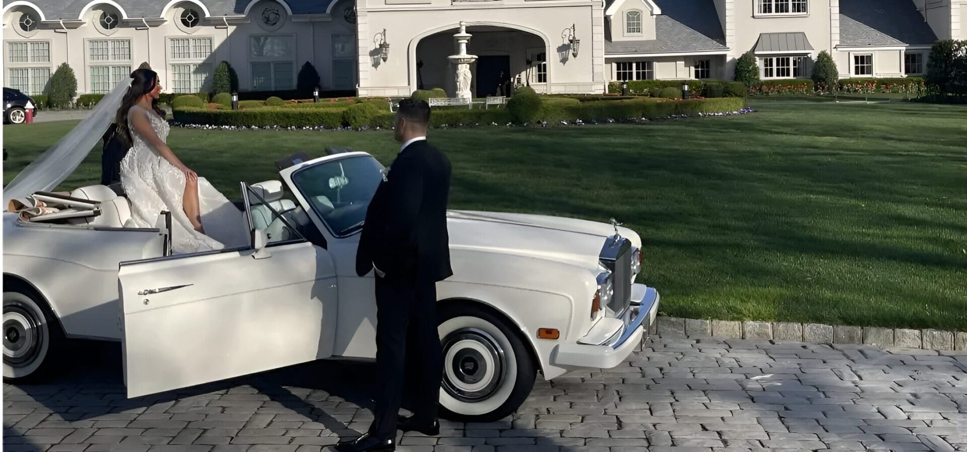 A Person In A Suit Standing Beside A White Car